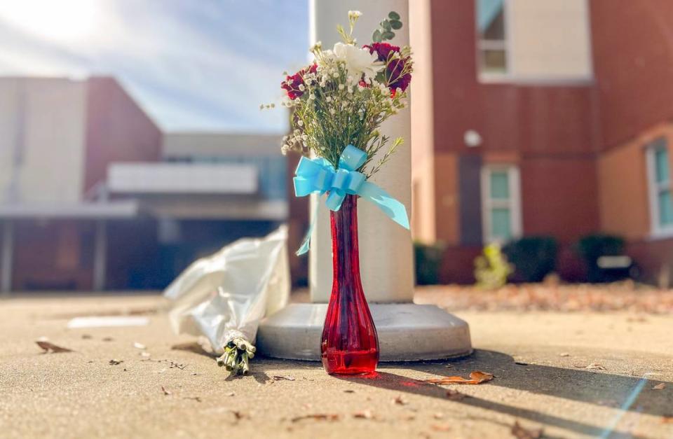 Flowers sit it at the base of a flagpole at Southeast Raleigh High School Tuesday morning, Nov 28, 2023. A 14-year-old has been charged with fatally stabbing a student and injuring another during a fight at the school on Monday morning.