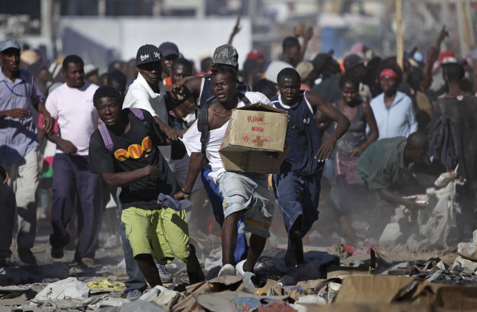 <p>A man runs with a box during sporadic looting in the aftermath of the Jan. 12 earthquake in Port-au-Prince, Thursday, Jan. 28, 2010. (Photo: Ariana Cubillos/AP) </p>