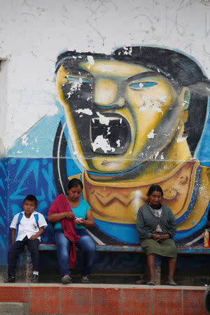 People sit next to a mural in Toribio, Cauca, Colombia, February 9, 2016. REUTERS/Jaime Saldarriaga