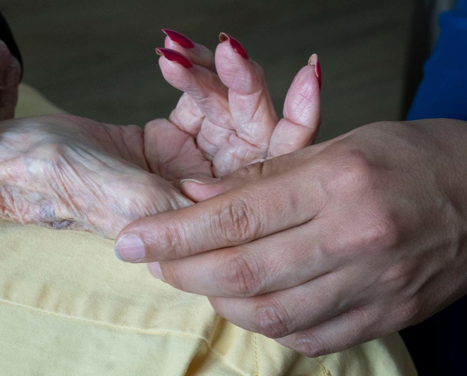 Hospice nurse holds hands with patient on April 25, 2022