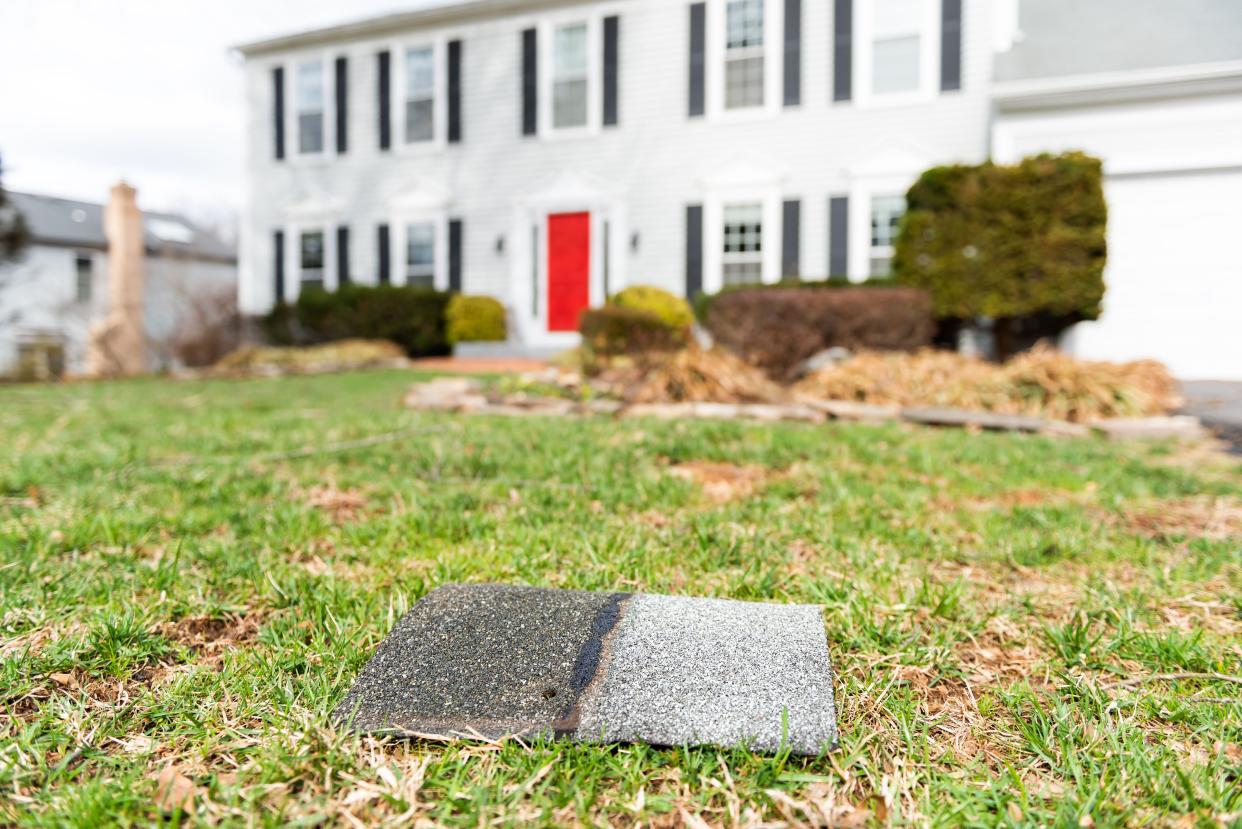 Roof shingle on front lawn in front of house