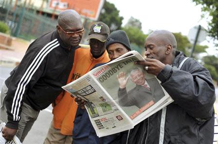 People read a newspaper on Vilakazi Street in Soweto, where former South African President Nelson Mandela resided when he lived in the township, December 6, 2013. REUTERS/Ihsaan Haffejee
