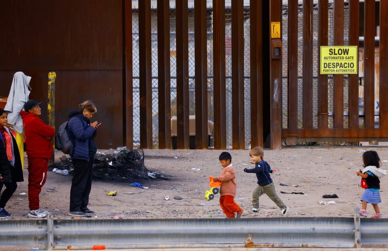 Migrants queue near the border fence, after crossing the Rio Bravo river, to request asylum in El Paso