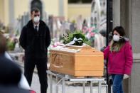 Una adolescente, también con mascarilla, se despide de un ser querido recientemente fallecido tocando el ataúd en el funeral. (PIERO CRUCIATTI/AFP via Getty Images)