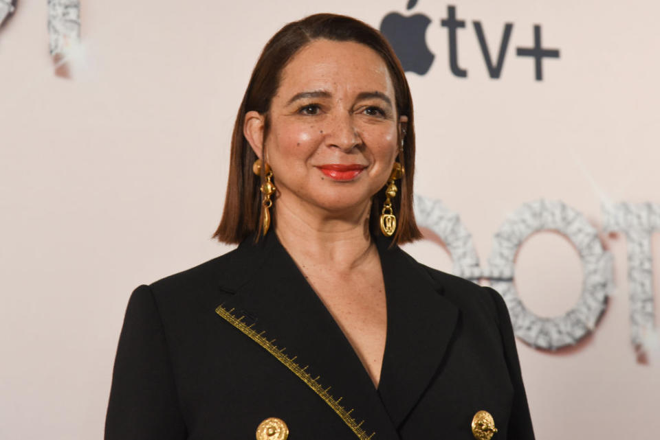 Maya Rudolph poses at an event in a black blazer with gold details