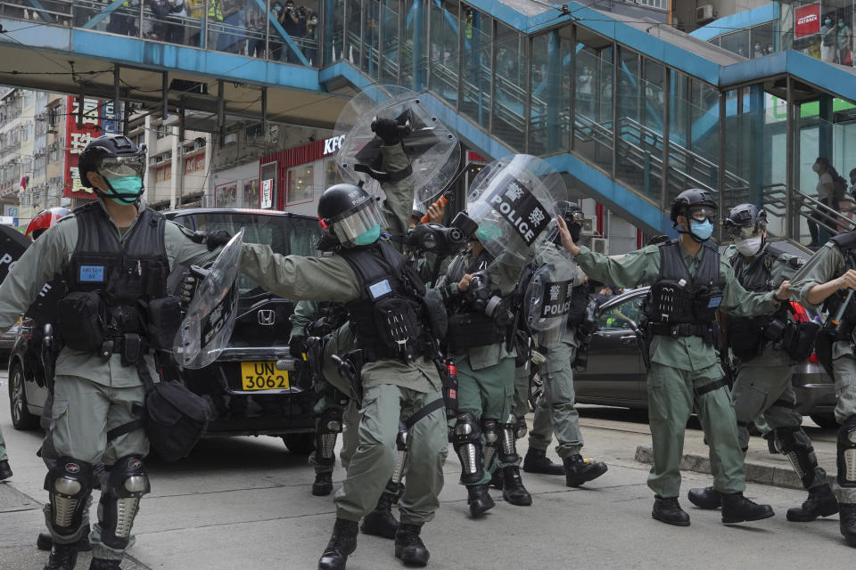 Riot police cover themselves with shields as hundreds of protesters march along a downtown street during a pro-democracy protest against Beijing's national security legislation in Hong Kong, Sunday, May 24, 2020. Hong Kong's pro-democracy camp has sharply criticised China's move to enact national security legislation in the semi-autonomous territory. They say it goes against the "one country, two systems" framework that promises the city freedoms not found on the mainland. (AP Photo/Vincent Yu)