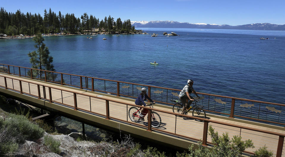 FILE - This June 25, 2019 file photo shows cyclists on the Tahoe East Shore Trail near Glenbrook, Nev. Water stored at Lake Tahoe has nearly reached its legal limit after snowmelt from a stormy winter left behind enough to potentially last through up to three summers of drought. The lake has been within an inch of its maximum allowed surface elevation of 6,229.1 feet above sea level for more than three weeks and crept to within a half-inch this week. (Jason Bean/The Reno Gazette-Journal via AP, File)