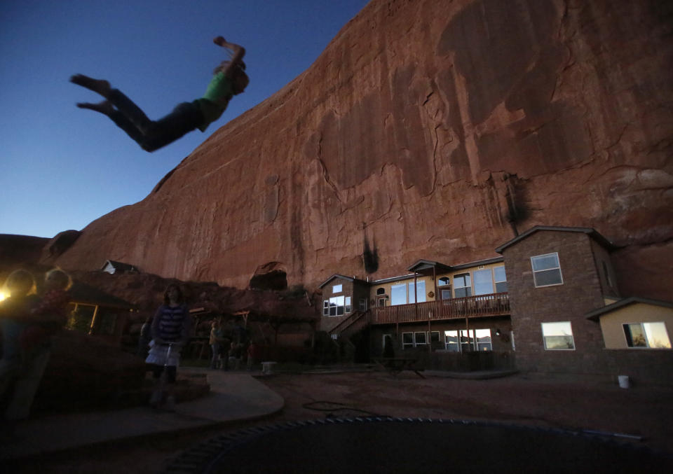 Girls play on a trampoline near a home blasted from a from a rock wall at the Rockland Ranch community outside Moab