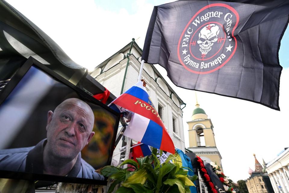 A flag bearing the logo of private mercenary group Wagner flutters above a portrait of late head of Wagner paramilitary group, Yevgeny Prigozhin at a makeshist memorial in Moscow, on Aug. 27, 2023. (Photo by NATALIA KOLESNIKOVA/AFP via Getty Images)