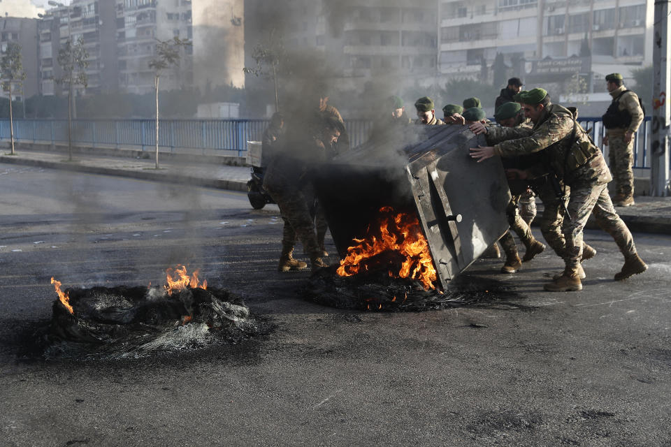 Lebanese army soldiers try to remove burning tires which were set on fire by the anti-government protesters to block the southern entrance of a highway during a protest against the newly formed cabinet, in Beirut, Lebanon, Monday, Jan. 27, 2020. (AP Photo/Hussein Malla)