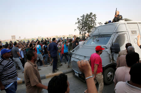 FILE PHOTO: Egyptians shout slogans against the government as they stand near a police vehicle during the funeral of Syed Tafshan, who died in clashes with residents of the Nile island of el-Warraq "Geziret El-Warraq" when security forces attempted to demolish illegal buildings, in the south of Cairo, Egypt July 16, 2017. REUTERS/Amr Abdallah Dalsh/File Photo