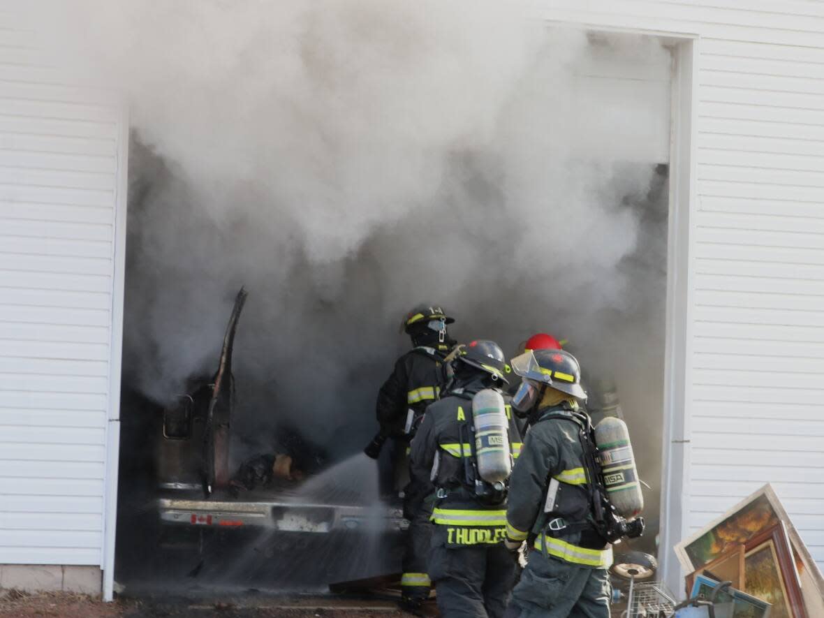 Amherst firefighters spray a wetting agent on a burning van inside the former pawnshop. (Town of Amherst - image credit)