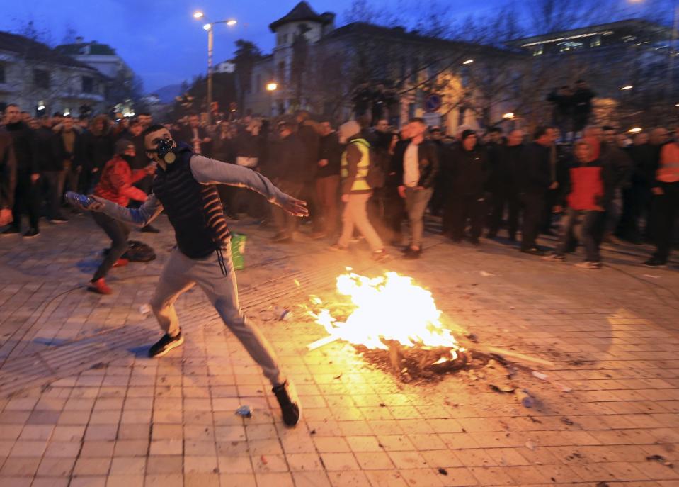 A young protester throws a plastic bottle during an antigovernment rally in Tirana, Tuesday, Feb. 26, 2019. Albanian opposition supporters have surrounded the parliament building and are demanding that the government resign, claiming it's corrupt and has links to organized crime. (AP Photo/Hektor Pustina)