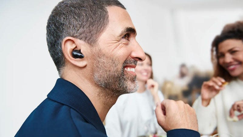 A person wearing the Sennheiser Conversation Clear Plus wireless earbuds in a crowded room.