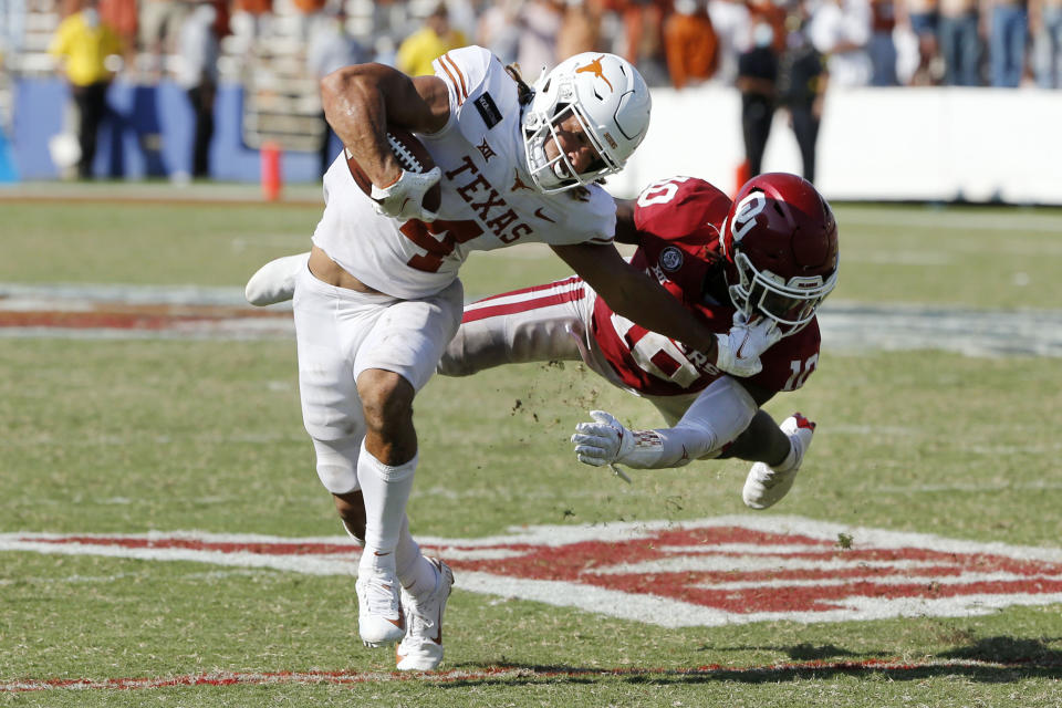 Texas wide receiver Jordan Whittington (4) tries to break a tackle from Oklahoma defensive back Pat Fields (10) during overtime of an NCAA college football game in Dallas, Saturday, Oct. 10, 2020. Oklahoma defeated Texas 53-45 in four overtimes.(AP Photo/Michael Ainsworth)