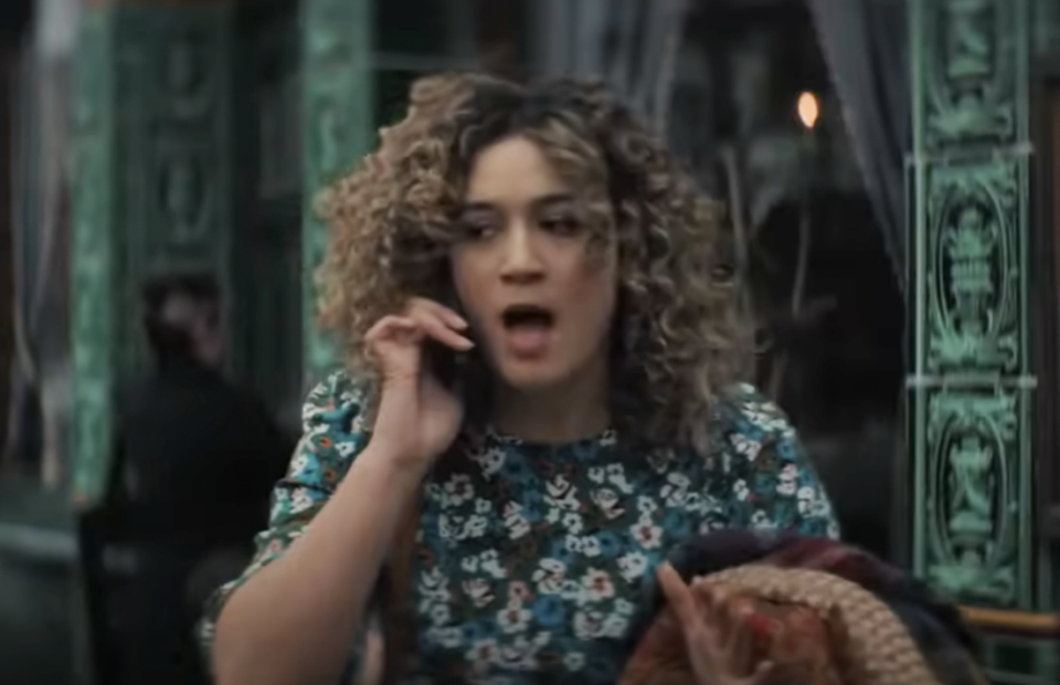 Person with curly hair, surprised expression, talks on phone, vintage-style backdrop
