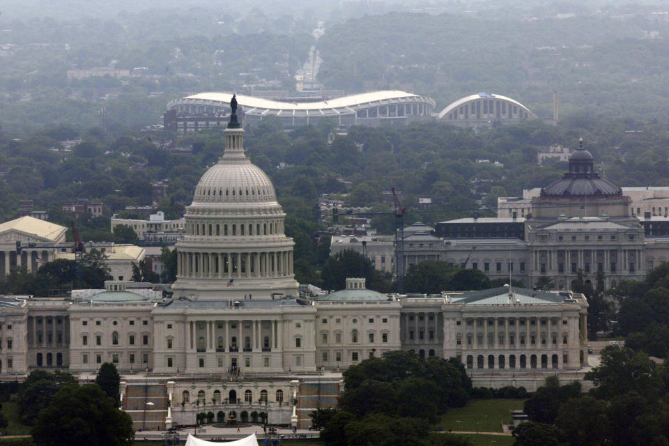 FILE - This May 27, 2004, file photo shows a view of RFK Stadium, background, and the Capitol building, in Washington. Growing up in the Washington suburbs during the 1960s, the local baseball team was a lost cause. A trip to the World Series like these Nationals? Forget it. Our Senators were out of it by opening day. So we found other things to root for under the wavy roof at D.C. Stadium and RFK. (AP Photo/Evan Vucci, Files)