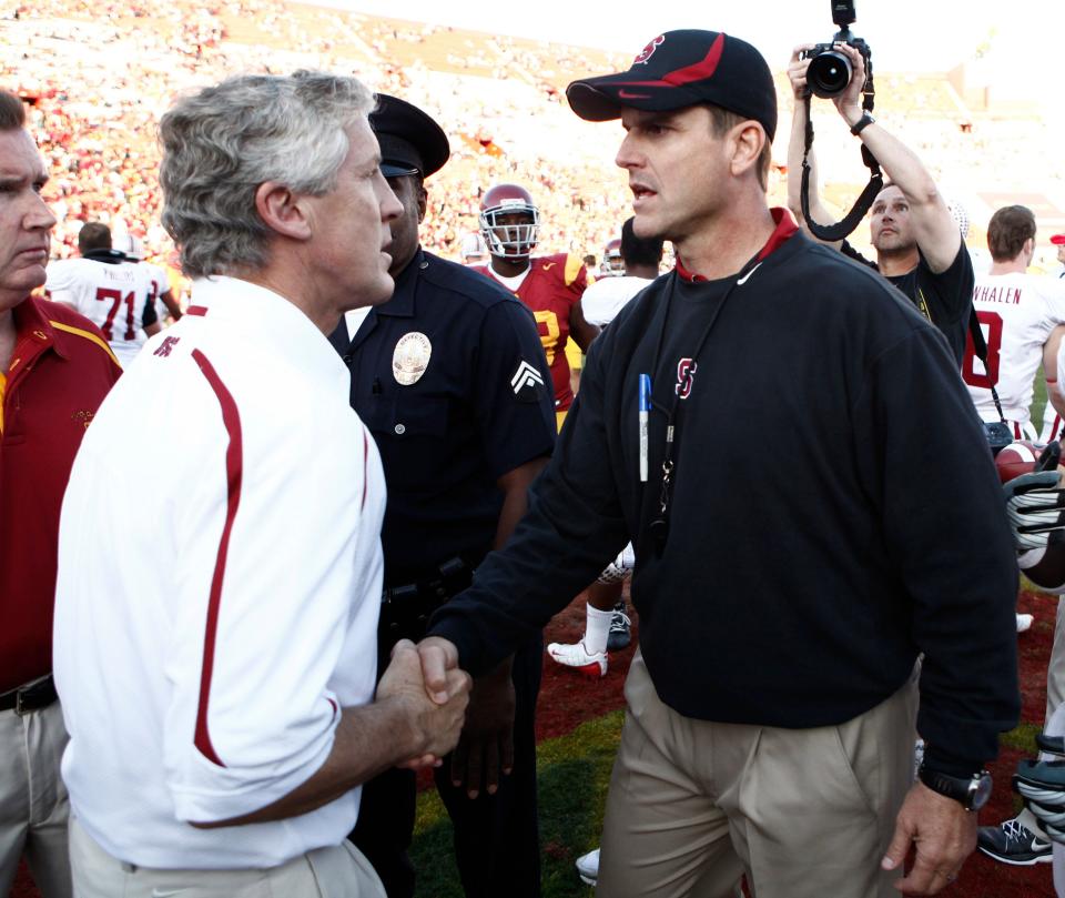 Former Southern California head coach Pete Carroll, left, and former Stanford head coach Jim Harbaugh greet each other after a college football game Nov. 14, 2009.