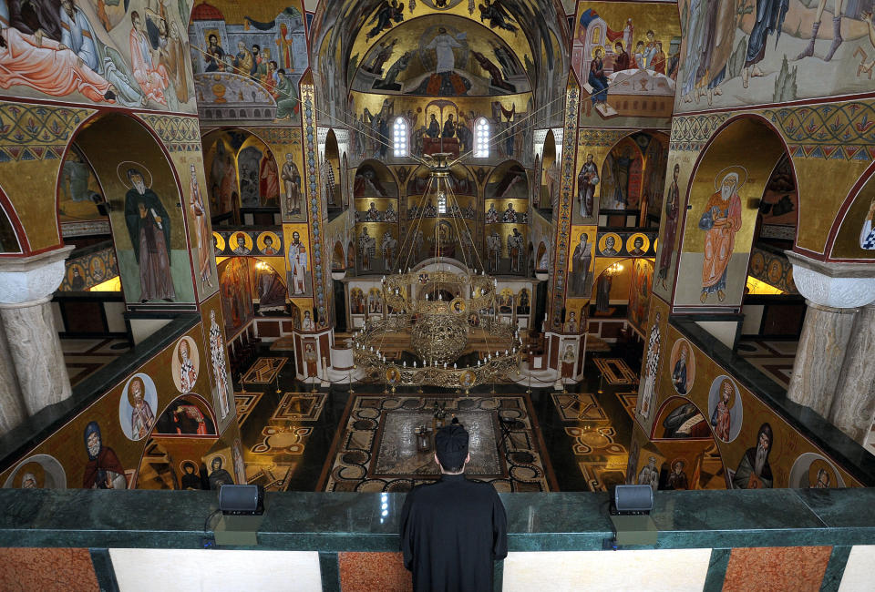 In this photo taken Tuesday, Feb. 4, 2014 an Orthodox priest stands in the Serbian Orthodox Church of Christ's Resurrection in Montenegro's capital Podgorica. The brightly-colored newly painted fresco in the Serbian Orthodox Church of Christ's Resurrection has triggered much attention and public controversy in this tiny former communist country. (AP Photo/Risto Bozovic)