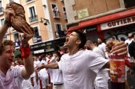 A reveler drinks from a wineskin while waiting for the launch of the 'Chupinazo' rocket, to mark the official opening of the 2022 San Fermin fiestas in Pamplona, Spain, Wednesday, July 6, 2022. The blast of a traditional firework opens Wednesday nine days of uninterrupted partying in Pamplona's famed running-of-the-bulls festival which was suspended for the past two years because of the coronavirus pandemic. (AP Photo/Alvaro Barrientos)