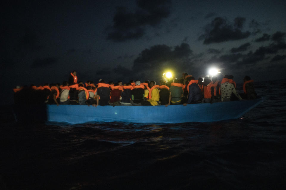 Dozens of migrants from different nationalities, mainly Somalia, Egypt and Morocco, including 14 minors and 4 women, wait to be assisted by a team of aid workers of the Spanish NGO Open Arms, after spending more than 20 hours at sea when fleeing Libya on board a precarious wooden boat, in international waters, in the Central Mediterranean sea, Tuesday, Sept. 8, 2020. (AP Photo/Santi Palacios)