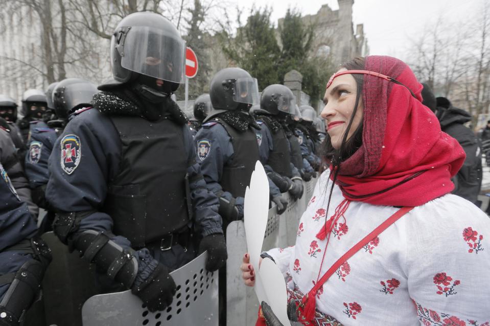 FILE - In this Sunday, Dec. 8, 2013 file photo a pro-European union activist holds a cut-out of a paper heart as she addresses police outside the Presidential office in Kiev, Ukraine. After two months of anti-government protests, modern Ukraine has never been so bitterly polarized. To be sure, Ukraine has long been divided. Russia and Europe have vied for dominance for centuries, causing deep cultural differences between the mostly Ukrainian-speaking western and central regions on the one hand, and the Russian-speaking east and south on the other. But as the crisis has deepened, each side has grown stronger in its convictions, and those who stood in the middle have been forced to choose sides. (AP Photo/Efrem Lukatsky, file)