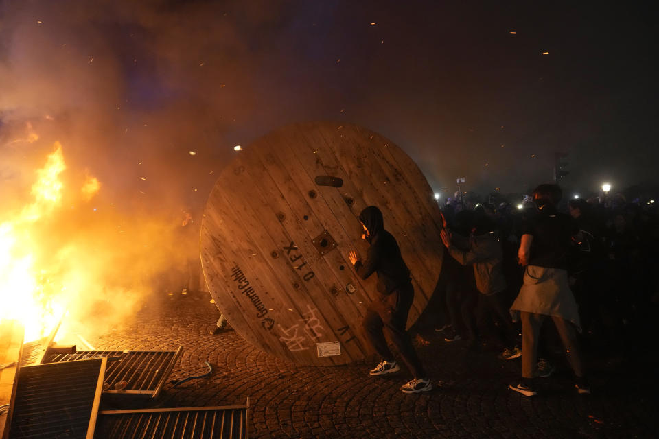 Manifestantes empujan una rueda de madera durante una protesta, el viernes 17 de marzo de 2023, en París. (AP Foto/Lewis Joly)