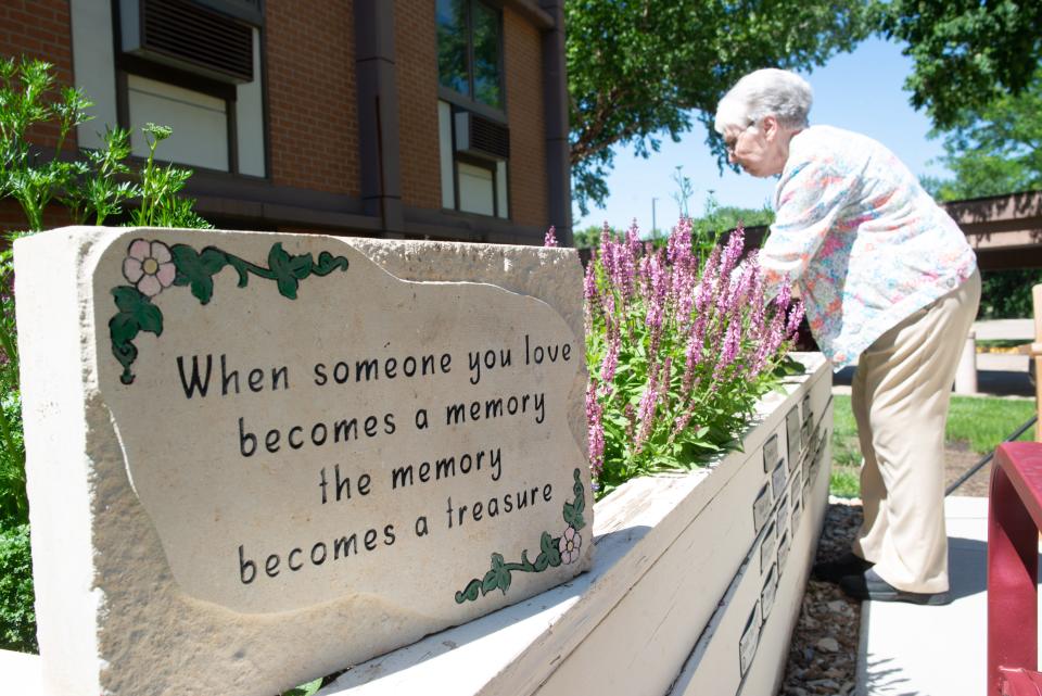 A stone reflects inspiring words of grief at the butterfly garden at Topeka Presbyterian Manor as Kay Jones tends to the plants Thursday afternoon.