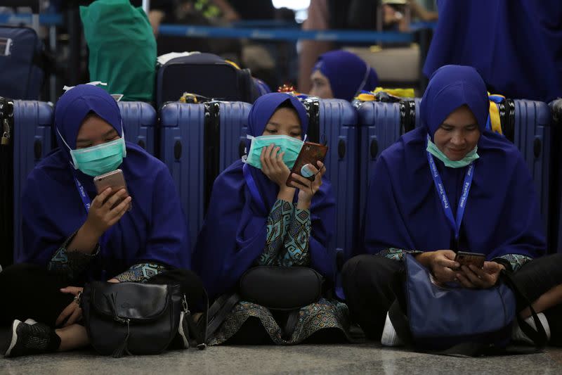 Passengers wearing masks use their mobile phones at Kuala Lumpur International Airport in Sepang