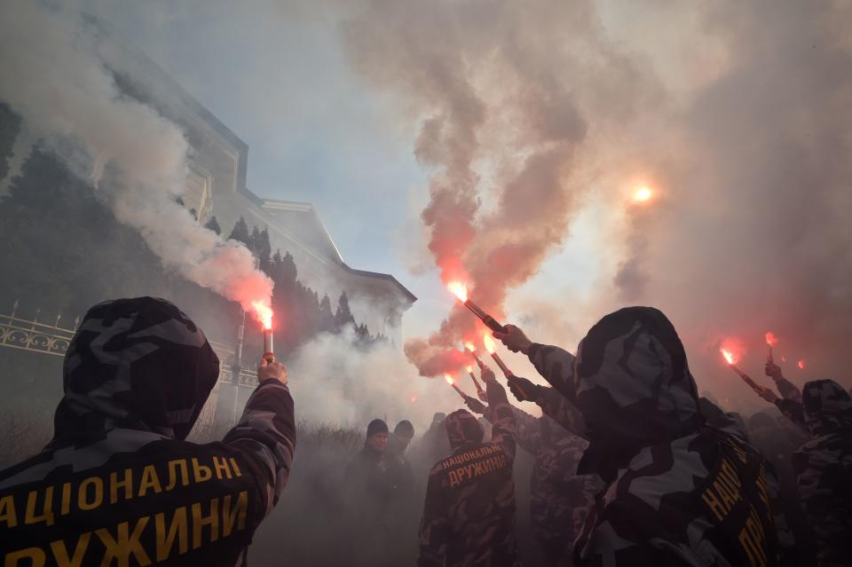 Activists and supporters of the Ukrainian far-right party National Corps burn flares in front of the private house which supposedly belongs to Svynarchuk in Kiev region on March 3, 2019. - Svynarchuk is the surname of the father and son, which translating to English as a pig, accused of allegedly enriching themselves by smuggling military equipment from Russia to Ukraine. On February 25, an independent media outlet aired a report alleging that people close to the president had smuggled parts for military equipment from Russia, causing the head of state, who faces a tough re-election bid next month, to come under fire. Accusations of ties involving Russia are extremely sensitive in Ukraine which has battled against Moscow-backed separatists since 2014, in a conflict that has claimed some 13,000 lives. (Photo by Genya SAVILOV / AFP)        (Photo credit should read GENYA SAVILOV/AFP/Getty Images)