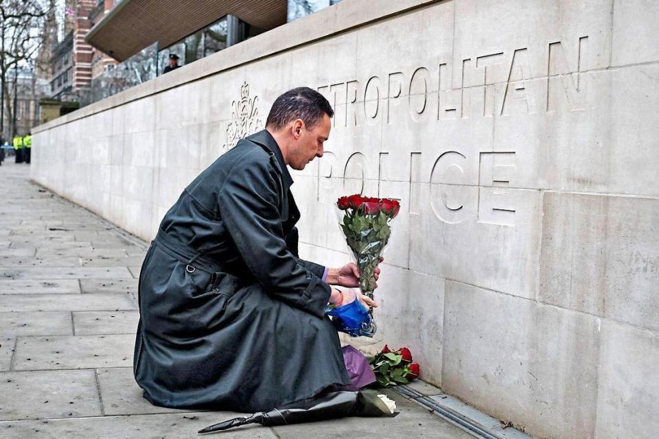 A simple tribute marking Wednesday’s attack: a man lays a bunch of flowers outside New Scotland Yard yesterday