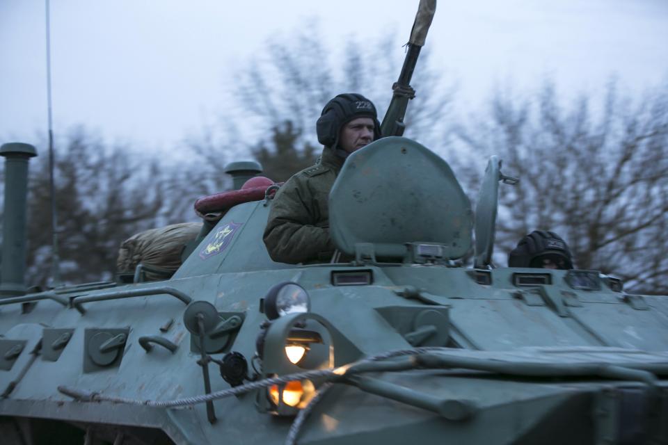 A Russian soldier sits on top of a military armoured personnel carrier (APC) as they drive on the road from Sevastopol to Simferopol