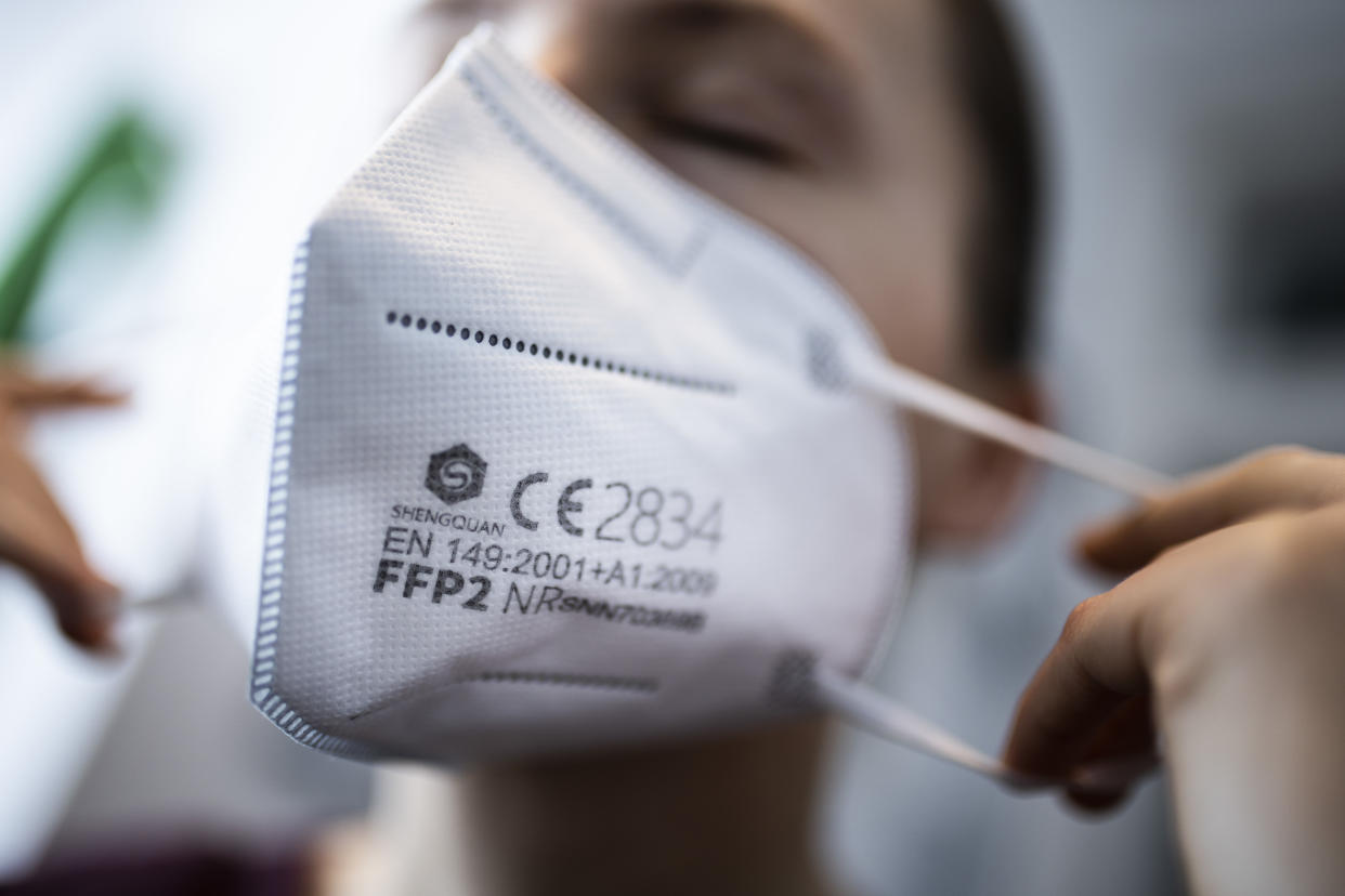 BERLIN, GERMANY - JANUARY 15: A woman puts on a FFP2 face mask  on January 15, 2021 in Berlin, Germany. In Germany there is a discussion about the obligation to wear a ffp2 masks in public. (Photo by Florian Gaertner/Photothek via Getty Images)