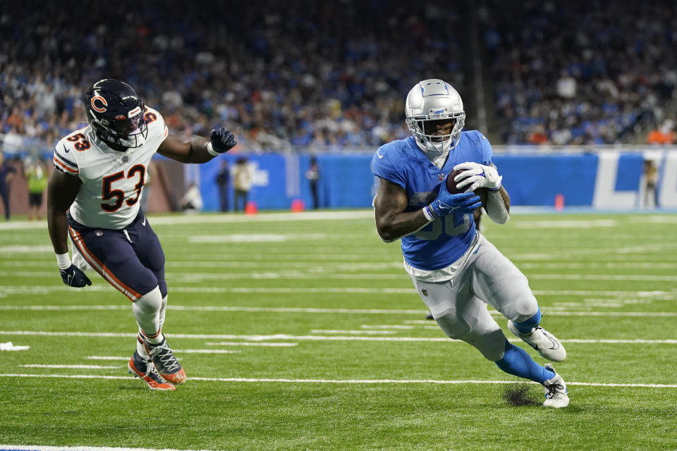 Detroit Lions running back Jamaal Williams (30), defended by Chicago Bears linebacker Nicholas Morrow (53), runs for a 2-yard touchdown during the second half of an NFL football game, Sunday, Jan. 1, 2023, in Detroit. (AP Photo/Paul Sancya)