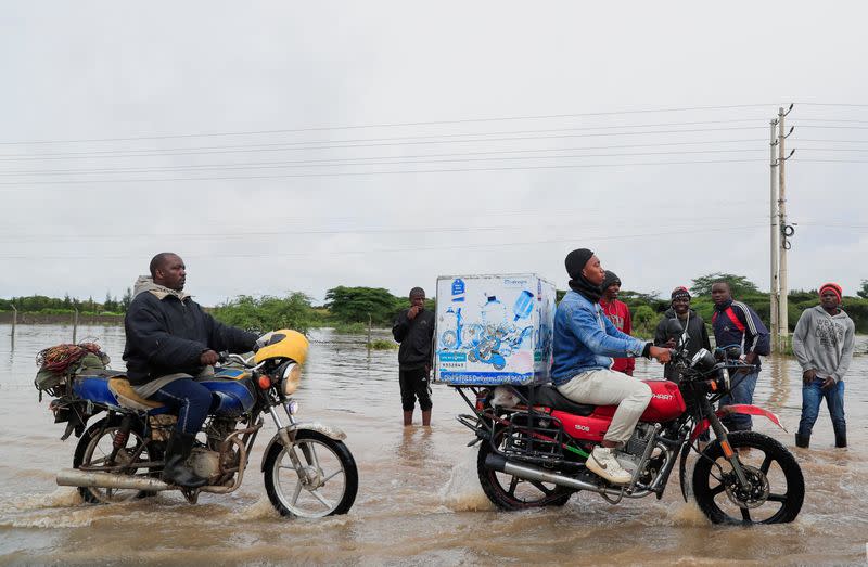 Motorcyclists ride along the Athi River-Namanga highway that was affected after a seasonal river burst its banks following heavy rainfall in Kitengela municipality of Kajiado County