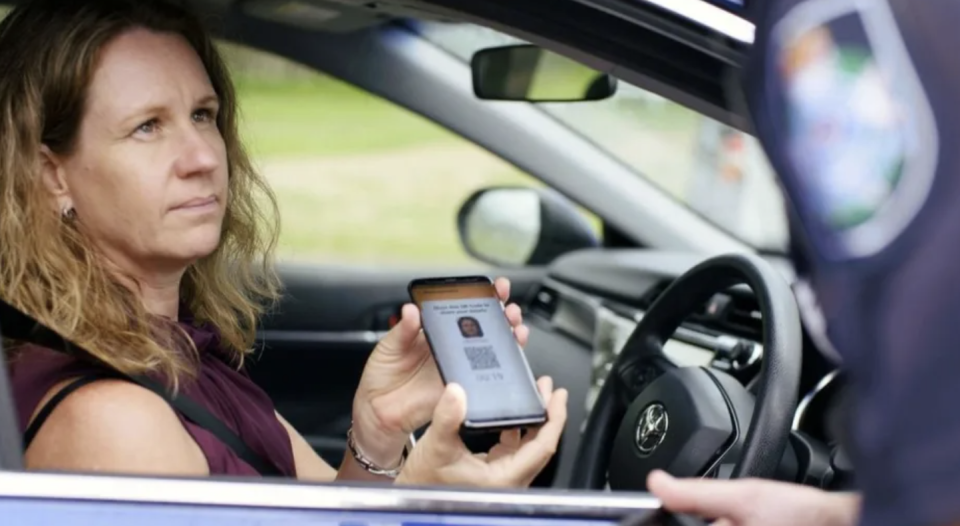 A Queensland driver displays her digital licence to a police officer.