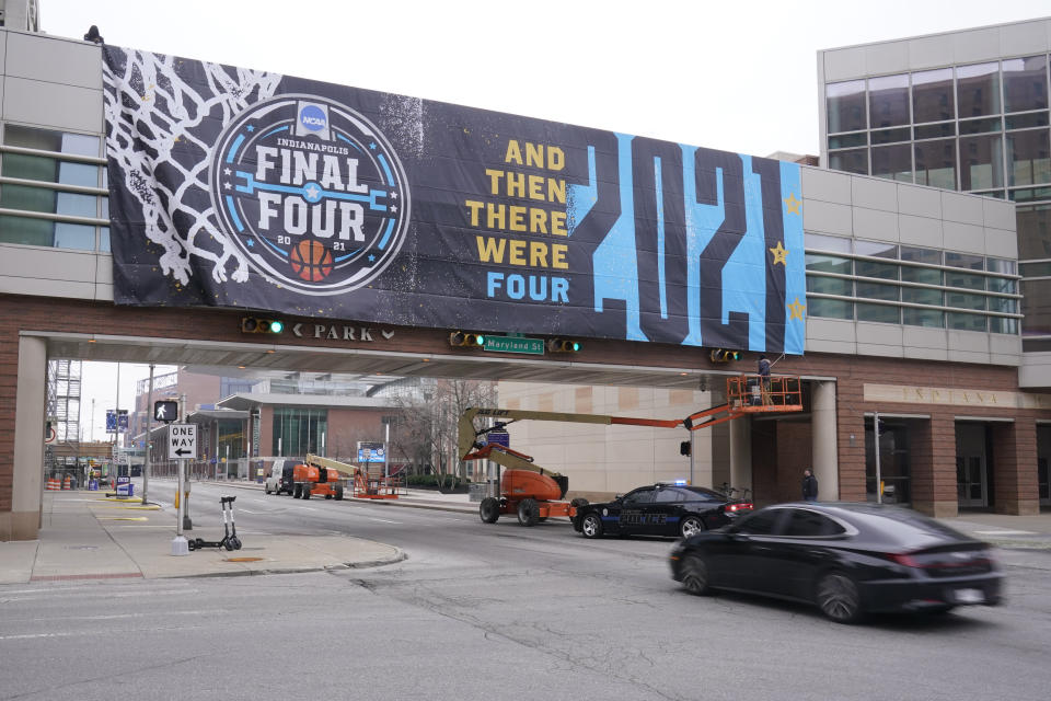 A worker ties down an NCAA college basketball tournament banner from a crosswalk, Wednesday, March 17, 2021, in Indianapolis. (AP Photo/Darron Cummings)