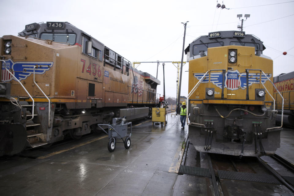 A Union Pacific worker walks between two locomotives that are being serviced in a railyard in Council Bluffs, Iowa, on Dec. 15, 2023. Recent layoffs at Union Pacific and BNSF, combined with an investment fund's campaign to take control of Norfolk Southern, are renewing concern among unions and regulators about how job cuts might affect safety and service. (AP Photo/Josh Funk)