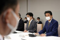 Japanese Prime Minister Shinzo Abe, right, declares a state of emergency during a meeting of the task force against the coronavirus at the his official residence in Tokyo, Tuesday, April 7, 2020. Abe declared a state of emergency for Tokyo and six other prefectures to ramp up defenses against the spread of the coronavirus. (Franck Robichon/Pool Photo via AP)