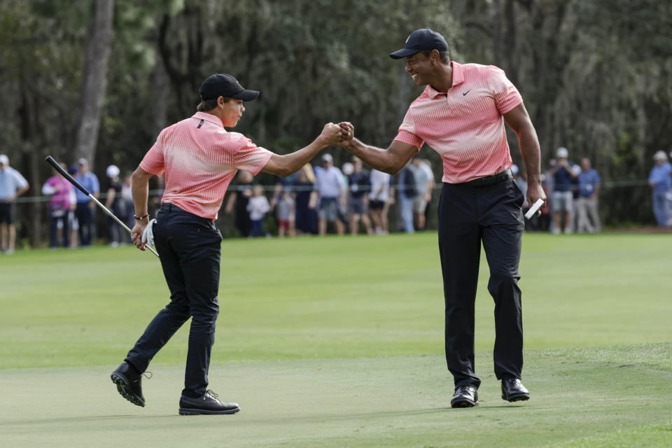 Tiger Woods, right and his son Charlie Woods bump fists on the ninth green during the first round of the PNC Championship golf tournament Saturday, Dec. 17, 2022, in Orlando, Fla. (AP Photo/Kevin Kolczynski)