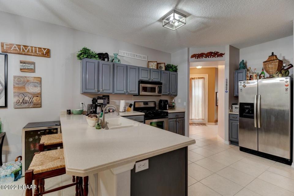 This beautifully designed open kitchen has stainless-steel appliances, a gas range and Corian countertops.