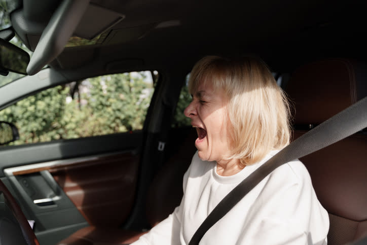 A woman yawning in her car