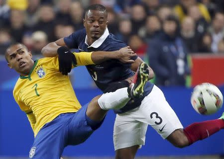 Brazil's Douglas Costa (L) fights for the ball with France's Patrice Evra during their international friendly soccer match at the Stade de France, in Saint-Denis, near Paris, March 26, 2015. REUTERS/Charles Platiau