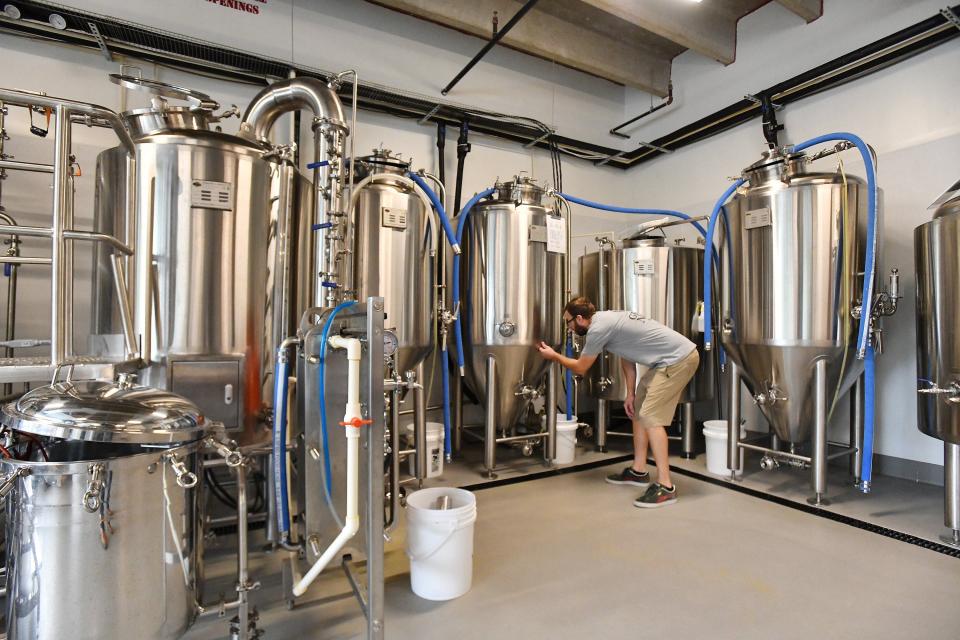 Jeremy Baker wipes a smudge off one of the tanks in the brewing room as he puts the final touches on Grace Note Brewing, his craft brewery at 4591 Lakeside Drive Suite 108 at Winward Sadler Point Marina on the Ortega River in Jacksonville.