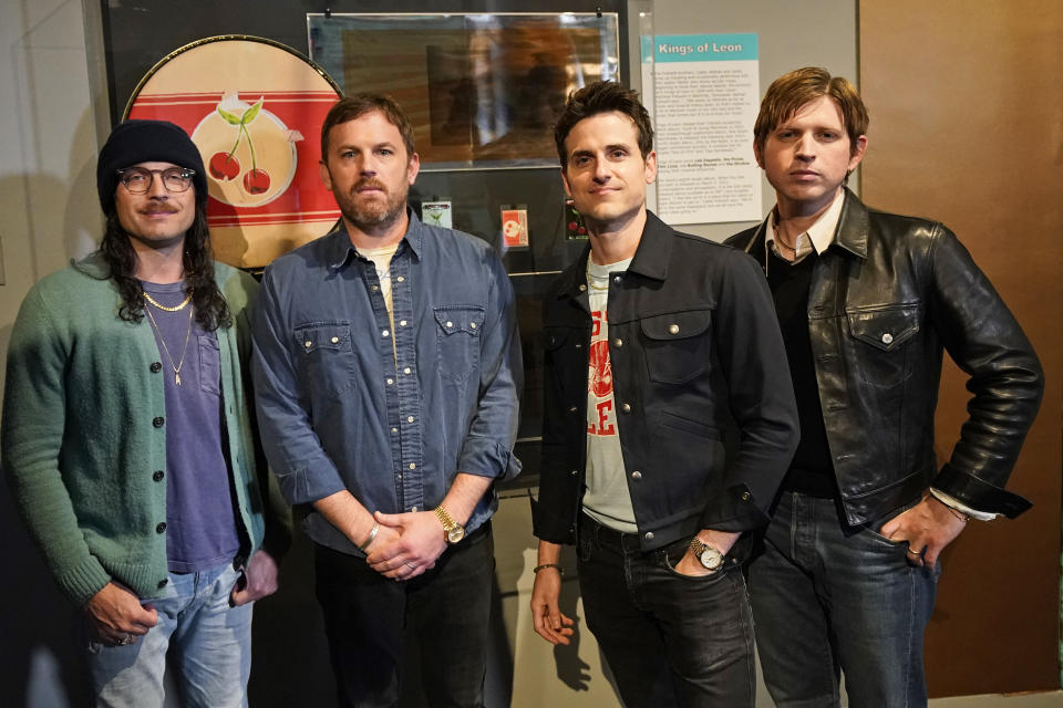 Rockers Kings of Leon, from left, Nathan, Caleb, Jared, and Matthew Followill, pose for a photo in front of their exhibit at the Rock and Roll Hall of Fame Thursday, April 29, 2021, in Cleveland. The band toured a new digital exhibit at the Rock and Roll Hall of Fame for the NFT (non-fungible token) launching before the rock band plays at the NFL draft, Thursday, April 29, 2021, in Cleveland. from left, Nathan, Caleb, Jared, and Matthew Followill are shown. (AP Photo/Tony Dejak)