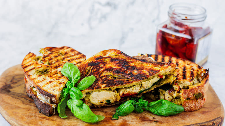 three chicken panini sandwiches on a cutting board