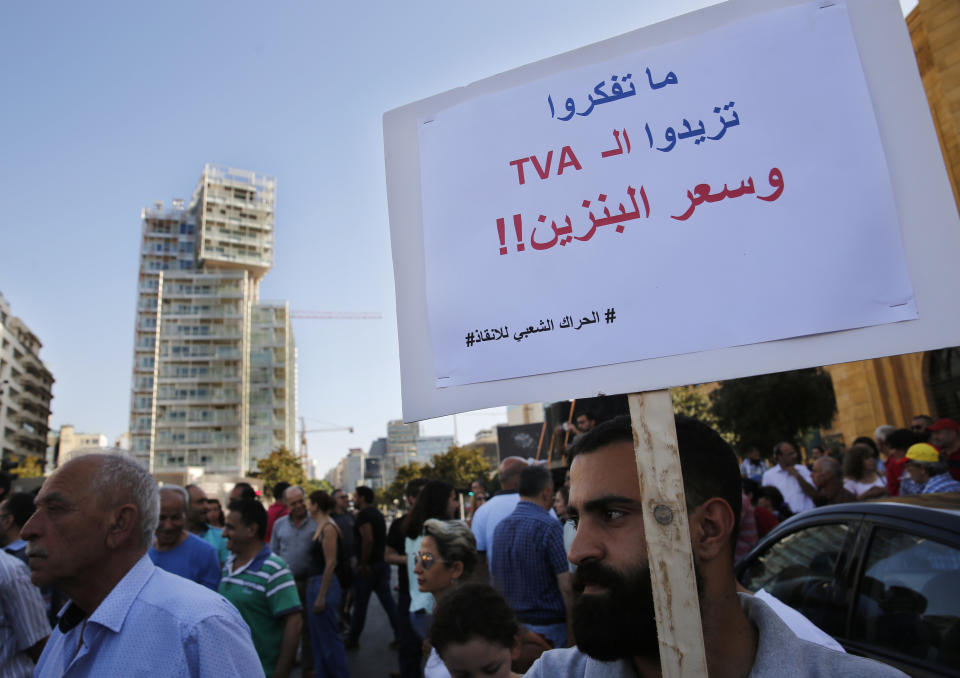 In this Tuesday, July 16, 2019 photo, a protester holds an Arabic placard that reads: "Do not think to increase the VAT tax and oil prices," during a protest near the parliament building where lawmakers and ministers are discussing the draft 2019 state budget, in Beirut, Lebanon. As the economic crisis deepens in Lebanon, so has the public’s distrust in the ability of the old political class, widely viewed as corrupt and steeped in personal rivalries, to tackle major reform. (AP Photo/Hussein Malla)