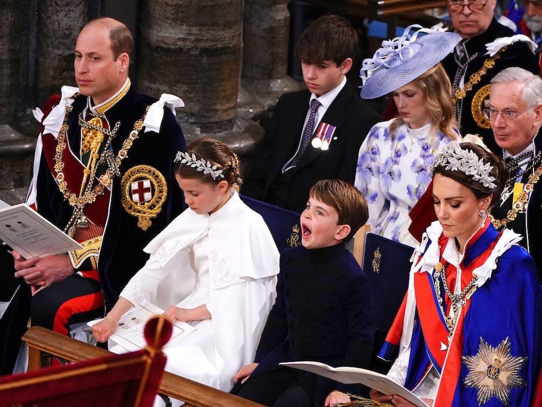 Prince Louis yawns in his seat at Westminster Abbey during King Charles' coronation, seated with his mother Kate Middleton, sister Princess Charlotte, and father Prince William.