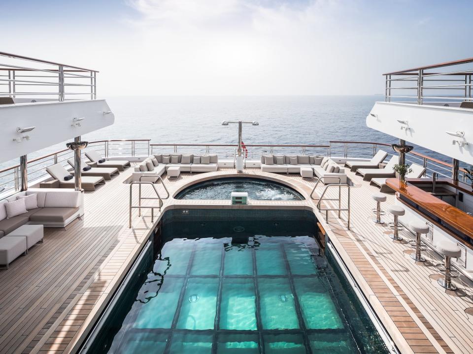 The pool on an outdoor deck next to a bar, outdoor lounge seeating.