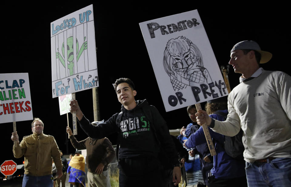 People holds signs at an entrance to the Nevada Test and Training Range near Area 51 Friday, Sept. 20, 2019, near Rachel, Nev. People gathered at the gate inspired by the "Storm Area 51" internet hoax. (AP Photo/John Locher)